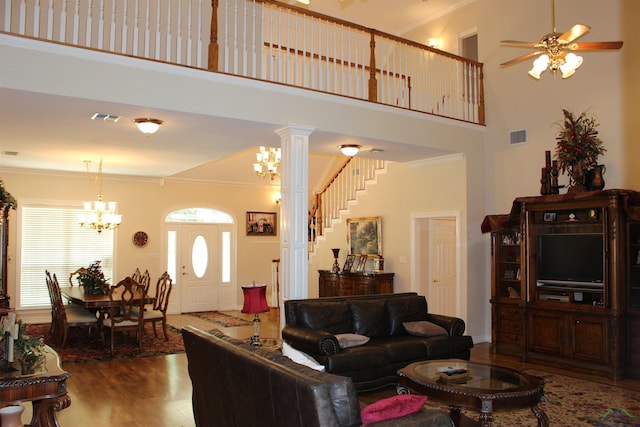 living room featuring ceiling fan, a high ceiling, decorative columns, hardwood / wood-style floors, and ornamental molding