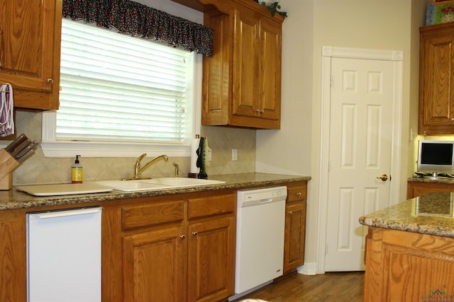 kitchen featuring white dishwasher, sink, decorative backsplash, dark hardwood / wood-style floors, and light stone countertops