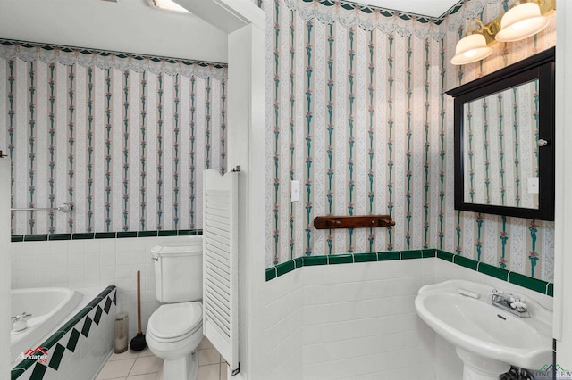 bathroom with sink, tile patterned flooring, toilet, a bathtub, and tile walls