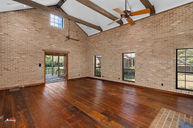 unfurnished living room with brick wall, beam ceiling, and high vaulted ceiling