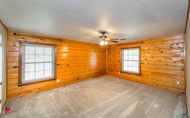 carpeted empty room featuring wooden walls and ceiling fan