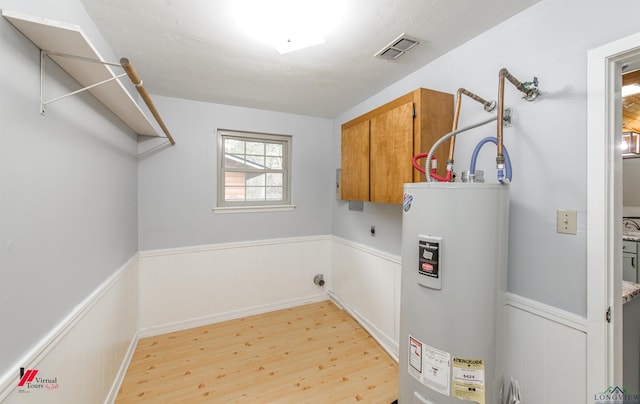 laundry area with electric water heater, hookup for an electric dryer, and light hardwood / wood-style floors