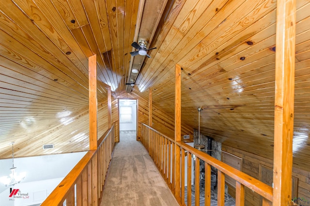 hallway featuring vaulted ceiling, light carpet, wood walls, and wooden ceiling