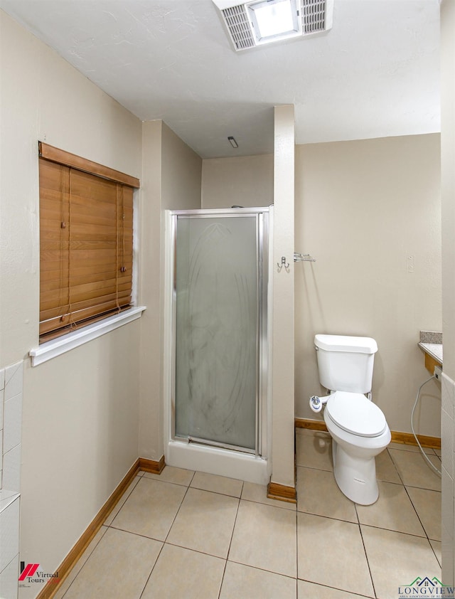 bathroom featuring toilet, tile patterned flooring, and an enclosed shower