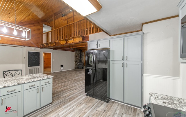 kitchen with light hardwood / wood-style flooring, decorative light fixtures, wood ceiling, black refrigerator with ice dispenser, and a wood stove