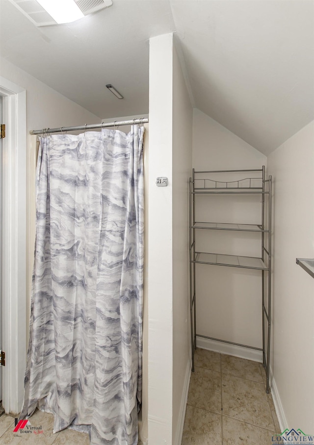 bathroom featuring tile patterned flooring and vaulted ceiling