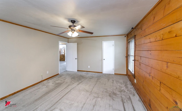 carpeted spare room featuring ceiling fan, crown molding, and wood walls