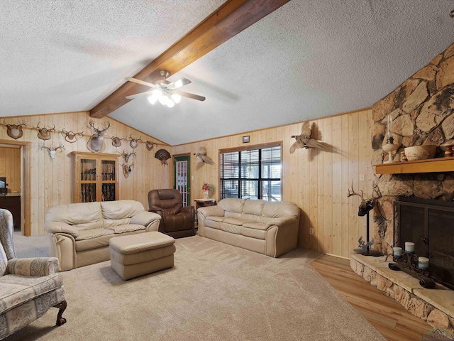 living room featuring vaulted ceiling with beams, ceiling fan, a textured ceiling, a fireplace, and light hardwood / wood-style floors