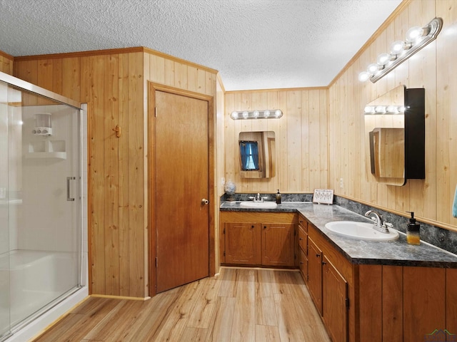 bathroom with crown molding, a textured ceiling, wooden walls, a shower with shower door, and hardwood / wood-style flooring