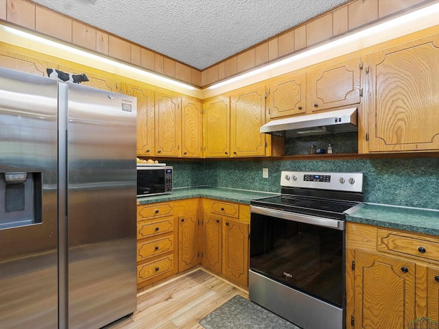 kitchen with a textured ceiling, stainless steel appliances, and light hardwood / wood-style flooring