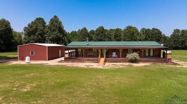 back of property with an outdoor structure, a yard, and a porch