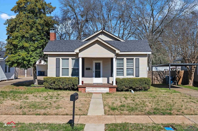 bungalow featuring a shingled roof, a chimney, and a front yard