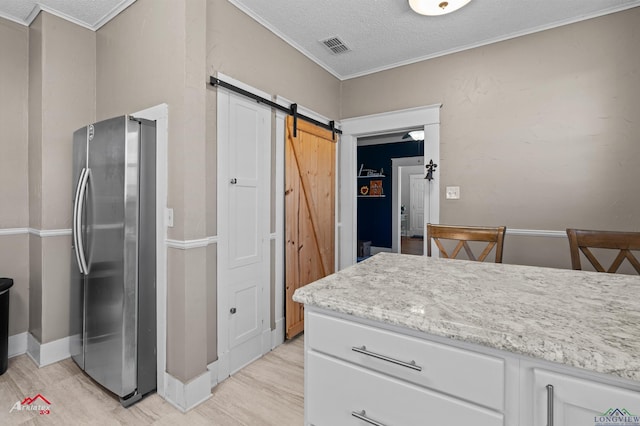 kitchen featuring crown molding, a barn door, light wood-style floors, freestanding refrigerator, and white cabinetry