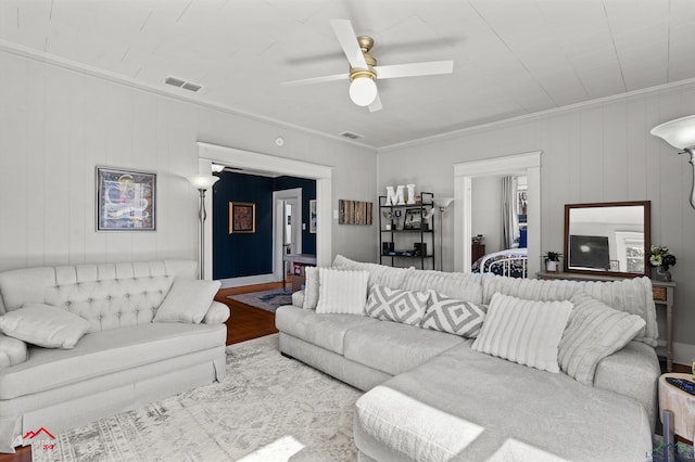 living room featuring ornamental molding, visible vents, ceiling fan, and wood finished floors