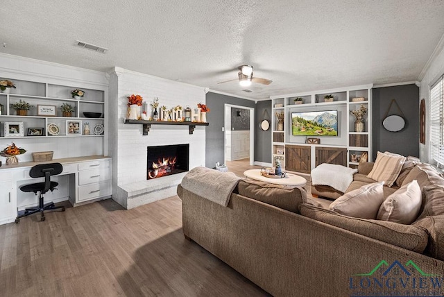 living room with a textured ceiling, built in features, and crown molding