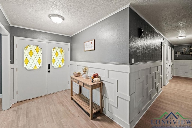 entrance foyer with a textured ceiling, light wood-type flooring, and crown molding