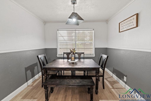 dining area with a textured ceiling, crown molding, and light hardwood / wood-style flooring