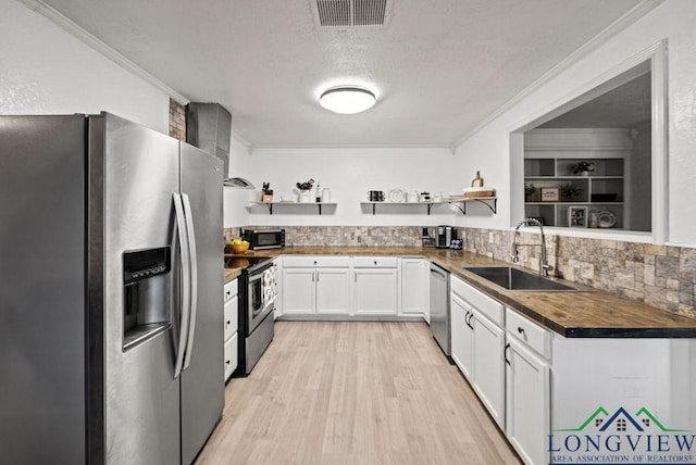 kitchen with white cabinets, sink, ornamental molding, butcher block counters, and stainless steel appliances