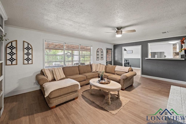 living room with hardwood / wood-style floors, ceiling fan, crown molding, and a textured ceiling