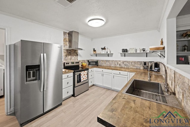 kitchen with appliances with stainless steel finishes, a textured ceiling, sink, wall chimney range hood, and white cabinetry