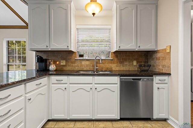 504 Lakewood Dr, Longview, TX 75604 - kitchen with stainless steel dishwasher, dark stone countertops, light tile patterned flooring, a sink, and backsplash