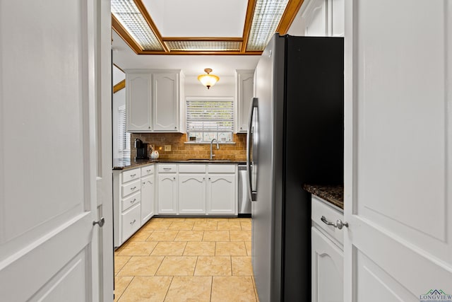 504 Lakewood Dr, Longview, TX 75604 - kitchen featuring light tile patterned floors, white cabinets, a sink, stainless steel appliances, and decorative backsplash