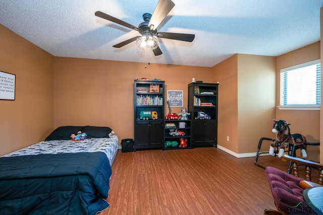 bedroom featuring ceiling fan, wood-type flooring, and a textured ceiling