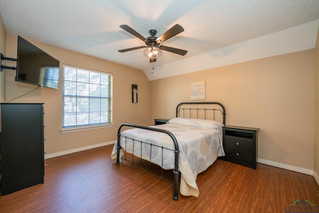 bedroom with a textured ceiling, ceiling fan, dark hardwood / wood-style flooring, and vaulted ceiling