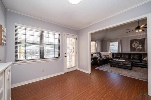 living room featuring ceiling fan, dark wood-type flooring, crown molding, vaulted ceiling, and a textured ceiling