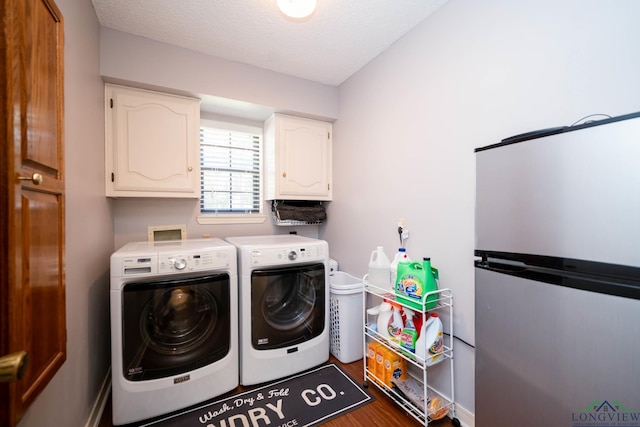 laundry room with a textured ceiling, cabinets, dark wood-type flooring, and washing machine and clothes dryer