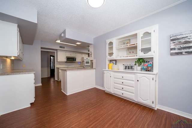 kitchen featuring a textured ceiling, tasteful backsplash, white cabinetry, and white oven