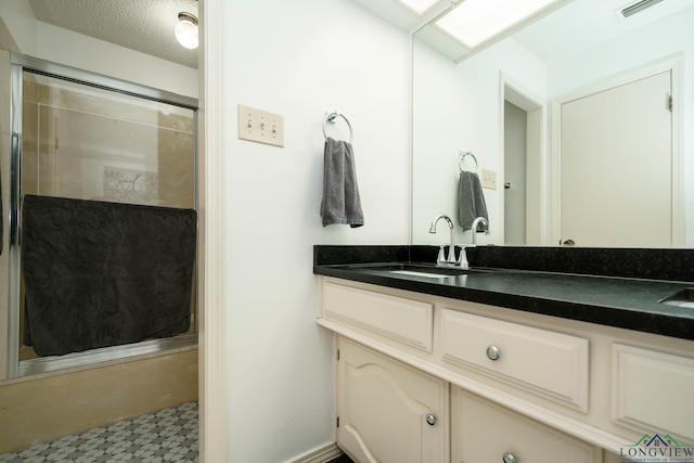 bathroom with vanity, a shower with door, and a textured ceiling