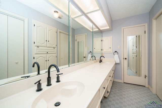 bathroom featuring tile patterned flooring, vanity, and a textured ceiling