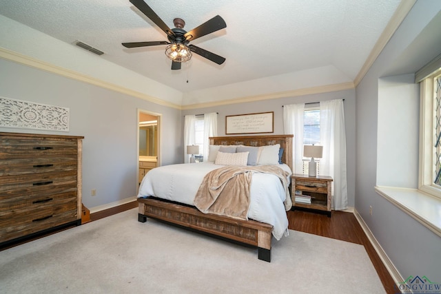 bedroom featuring connected bathroom, ceiling fan, a raised ceiling, dark hardwood / wood-style floors, and a textured ceiling