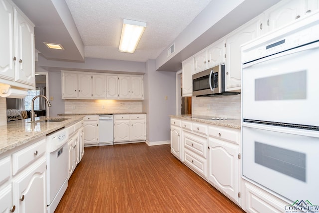 kitchen with a textured ceiling, sink, white cabinets, and white appliances