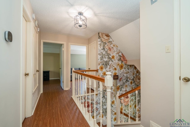 hall featuring hardwood / wood-style flooring, a textured ceiling, and vaulted ceiling