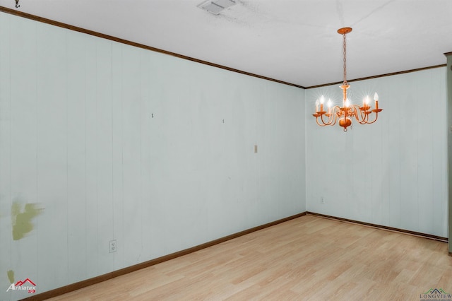 unfurnished room with a notable chandelier, light hardwood / wood-style floors, and crown molding