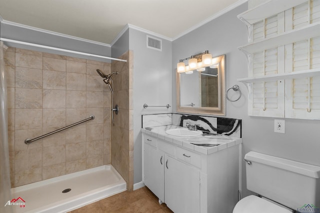 bathroom with tile patterned floors, a tile shower, vanity, crown molding, and toilet