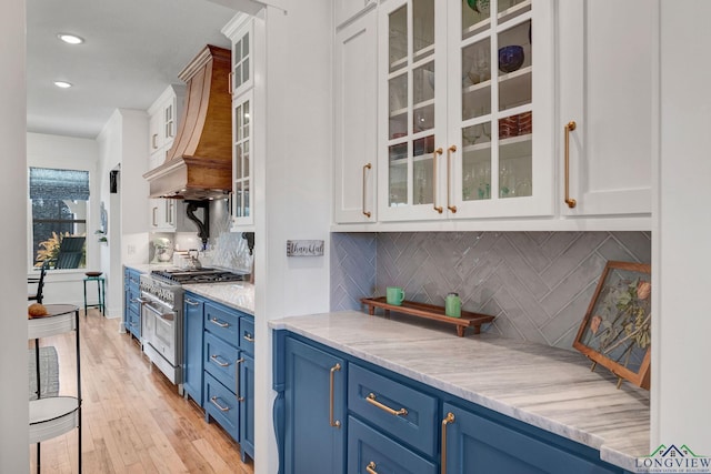 kitchen with high end stainless steel range oven, white cabinetry, and light stone countertops