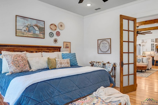 bedroom featuring ornamental molding, french doors, hardwood / wood-style floors, and ceiling fan with notable chandelier