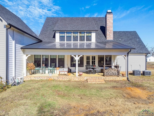 rear view of house featuring central air condition unit, a patio, and a lawn