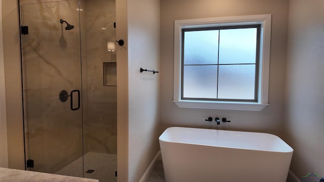 bathroom featuring a stall shower, baseboards, and a soaking tub