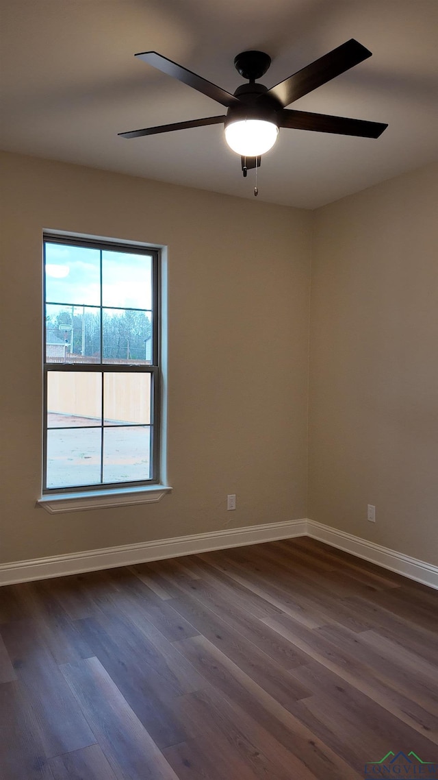 spare room with dark wood-style flooring, a ceiling fan, and baseboards