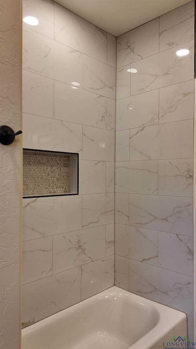 bathroom featuring a textured wall and shower / bath combination