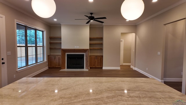 unfurnished living room with dark wood finished floors, a fireplace with flush hearth, ornamental molding, ceiling fan, and baseboards