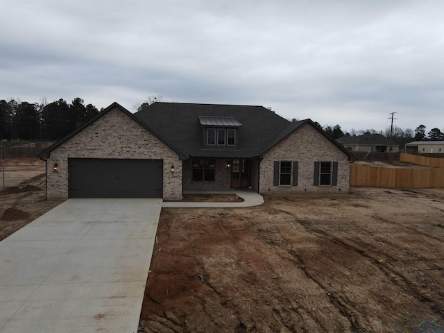 view of front of home featuring brick siding, driveway, an attached garage, and fence