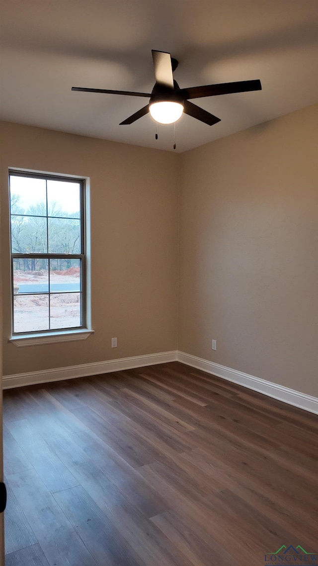 spare room featuring a ceiling fan, dark wood finished floors, and baseboards