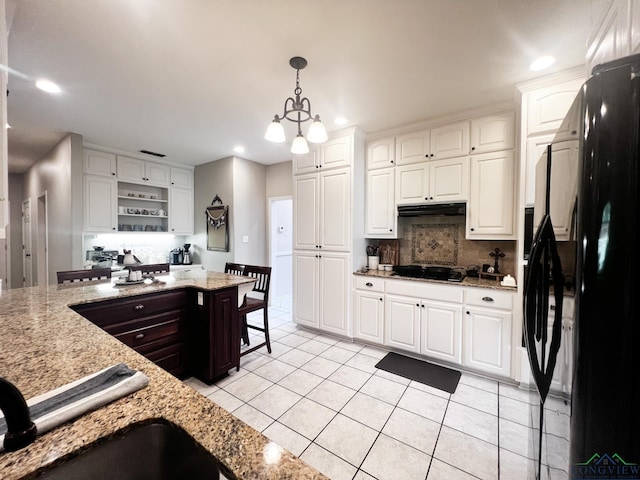 kitchen featuring white cabinets, decorative light fixtures, refrigerator, and a chandelier