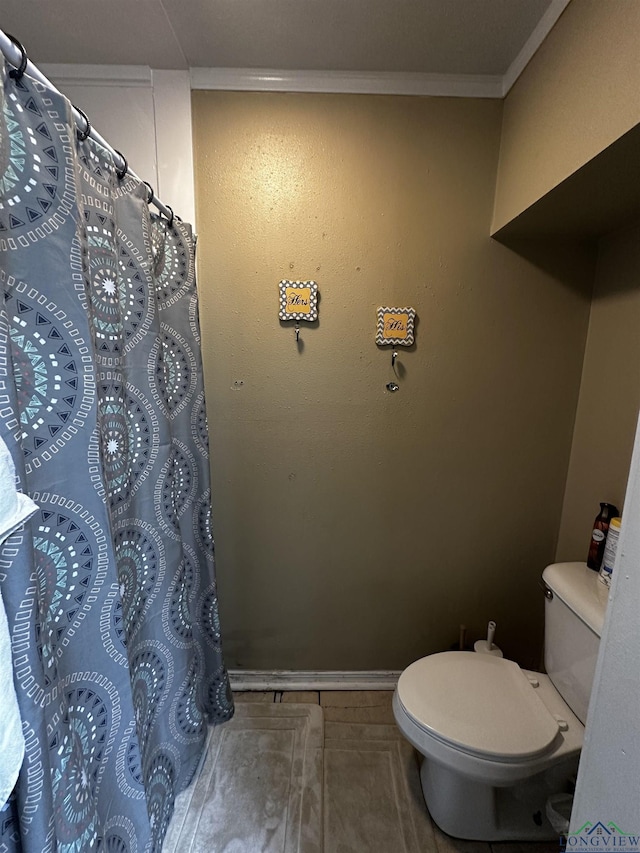 bathroom featuring curtained shower, tile patterned flooring, toilet, crown molding, and baseboards