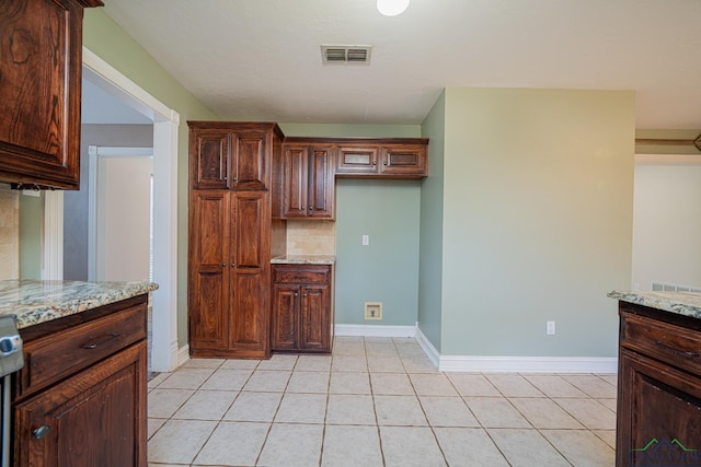 kitchen featuring light stone counters, decorative backsplash, and light tile patterned flooring